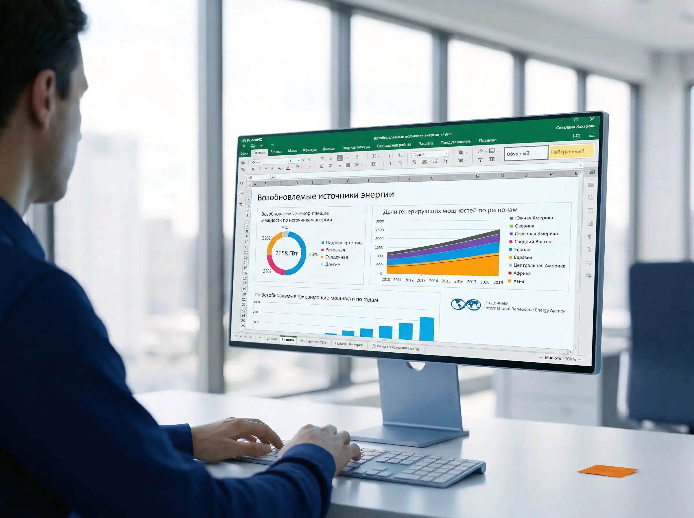 Офисный сотрудник за рабочим столом, на котором стоит монитор м интерфейсом Р-7-офис